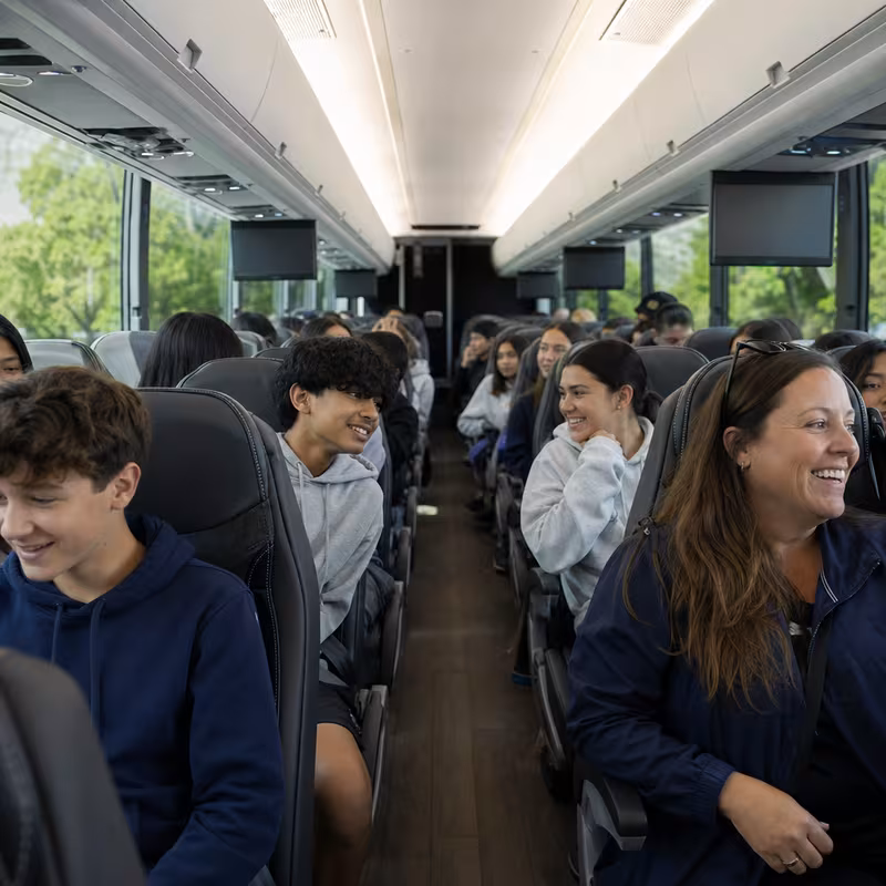 Group boarding a white charter bus for School Transportation transportation in Grand Rapids